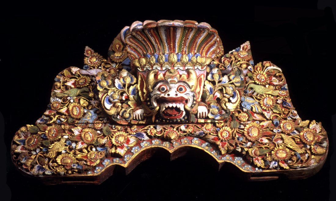 Hölzernes Brett mit Darstellung eines Dämonenkopfes (Boma), eingebettet in üppigen floralen Dekor