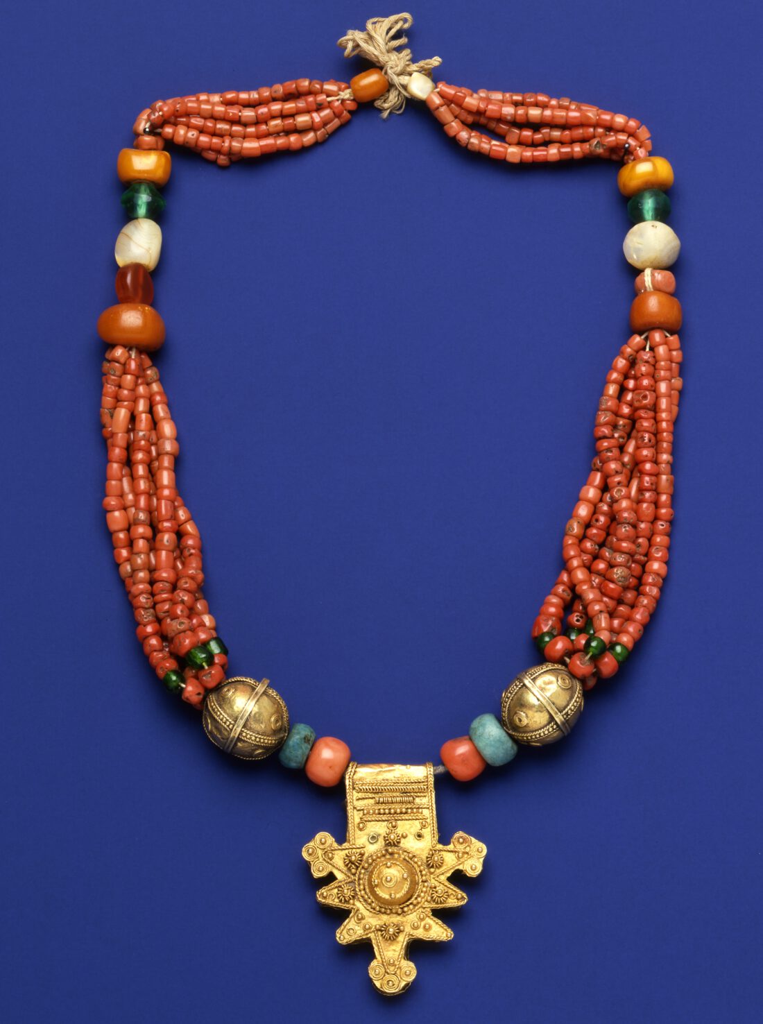 Necklace with mainly red beads and a gold pendant
