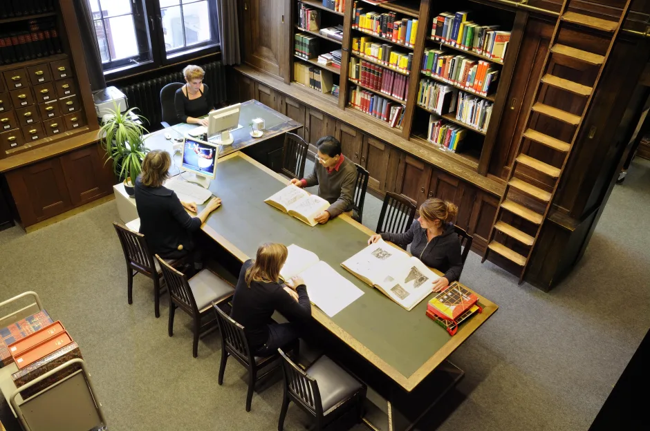 Lesende Personen inklusive beaufsichtigendes Bibliothekspersonal im Lesesaal der Bibliothek