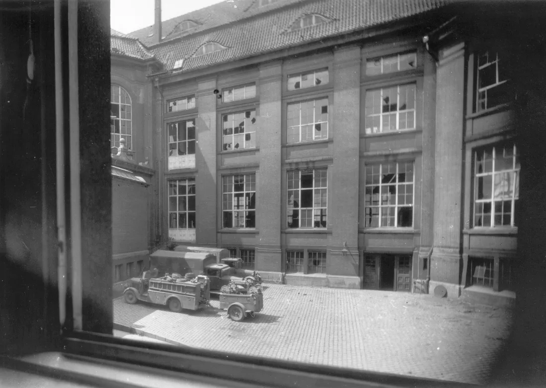Inner courtyard, destroyed windows, military vehicles, view from a window, b/w photograph