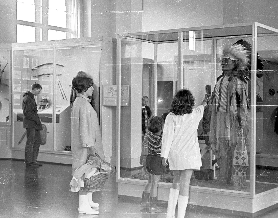 Showcases, dressed mannequin, exhibition visitors, rubber boots, b/w photograph