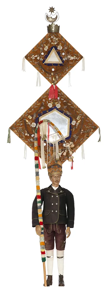 Male figure wearing a masked suit. Mirrors are attached to the mask, which is very high